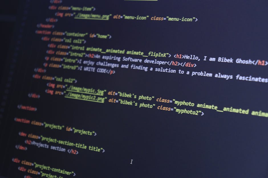 A close-up view of a person's hands typing on a MacBook laptop, which is placed on a dark, reflective surface. The laptop screen displays a code editor with lines of colorful code, including green, bl